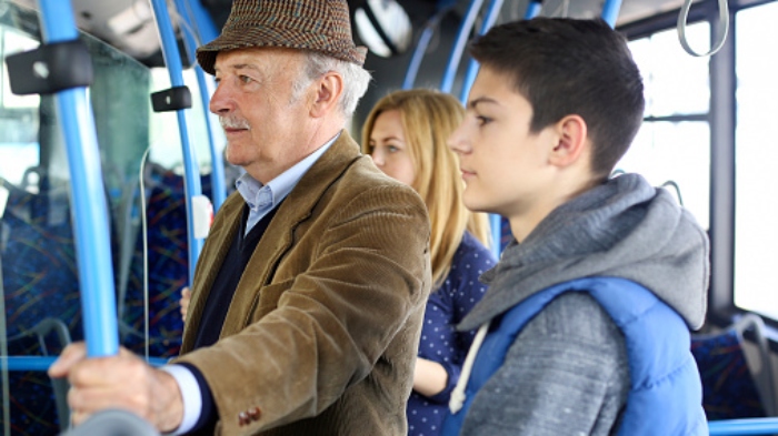 People riding on a public bus, teenager and a senior man