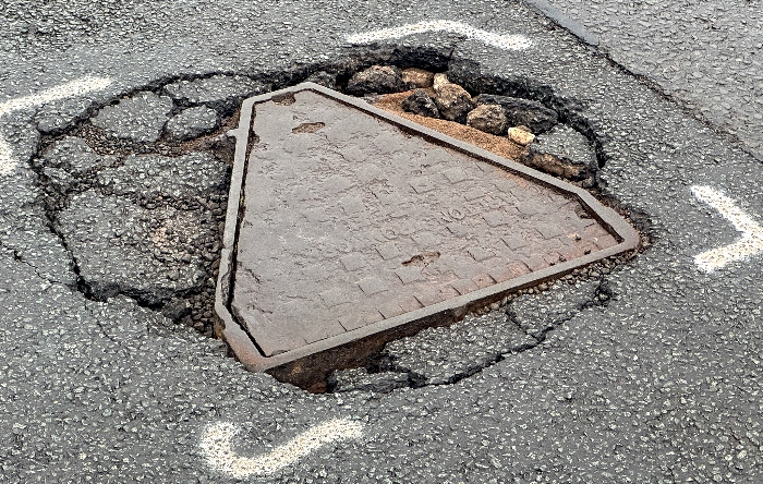 Loose manhole cover which also has adjacent damage on a busy road in Wistaston (1)