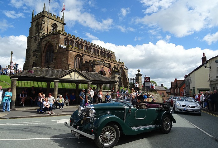 transport festival in Audlem - An Alvis in the parade passes St James Church