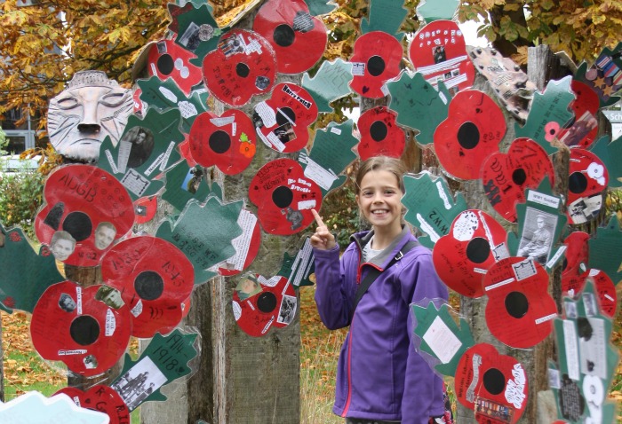 Mia Gleave pointing to her poppy made to remember her great grand dad, George Fisher, who served in WW2, poppy field