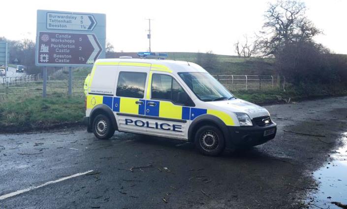 police car at closed lane with tree blown down by strong winds